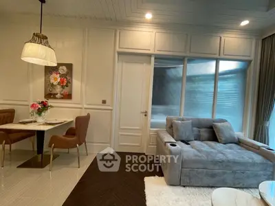 Elegant living room with plush sofa and stylish dining area, featuring modern lighting and chic decor.