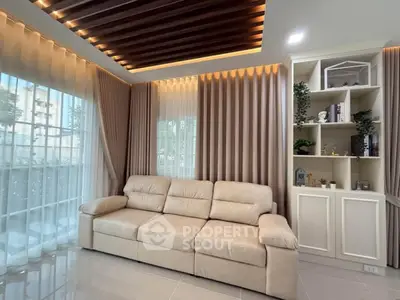 Elegant living room with modern beige sofa, stylish ceiling design, and floor-to-ceiling windows.