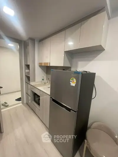 Modern kitchen with sleek cabinetry and stainless steel fridge in a compact layout.