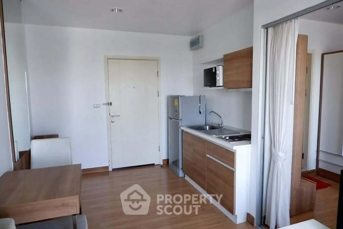 Modern compact kitchen with wooden cabinets and dining area in cozy apartment