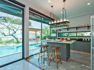 Luxurious kitchen with open layout and pool view, featuring modern island and stylish bar stools.