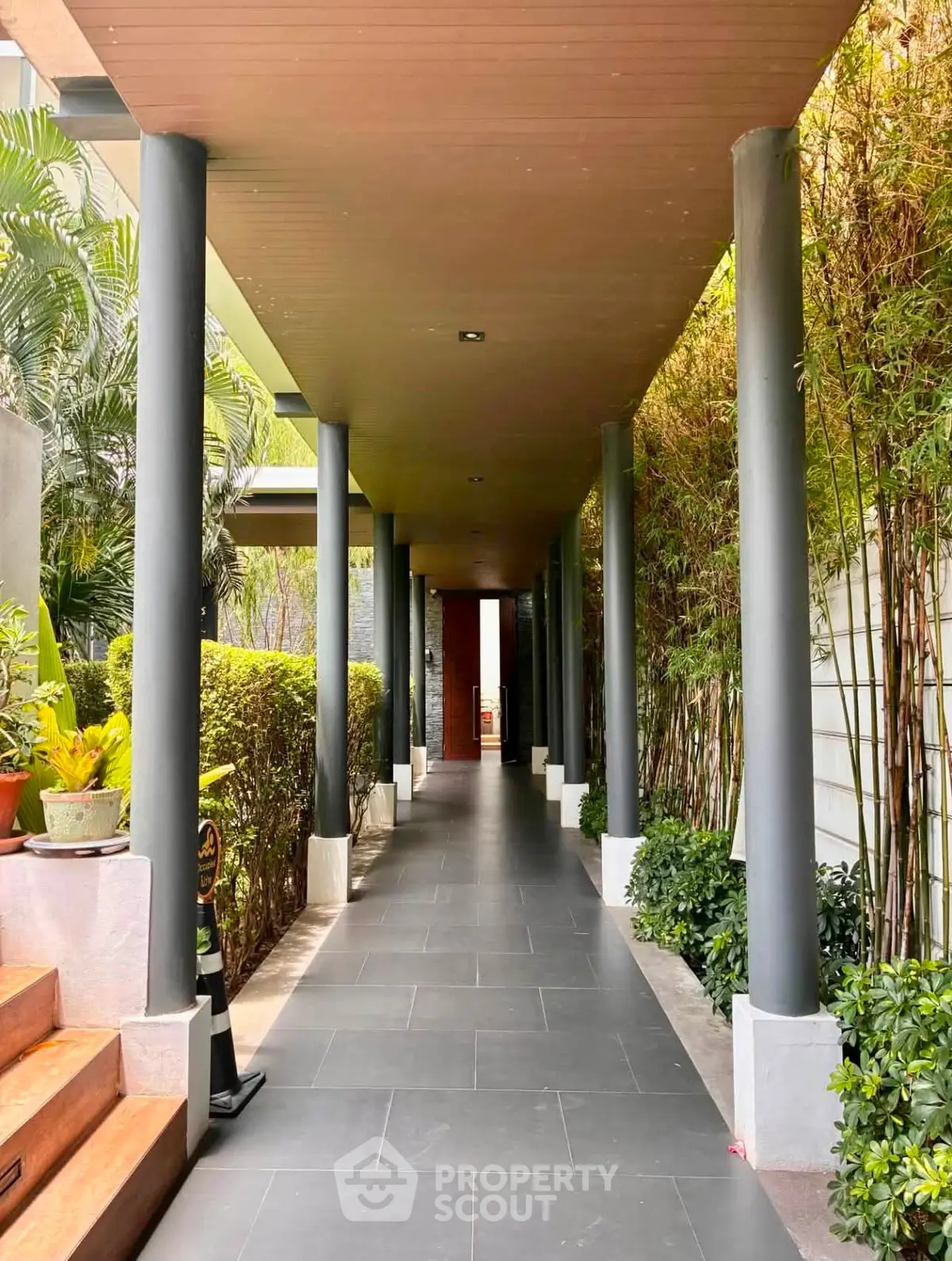 Elegant covered walkway with lush greenery and modern design elements in a luxury property.