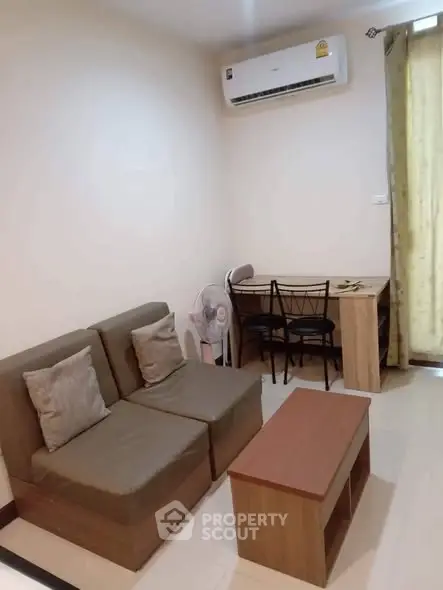 Cozy living room with modern sofa, air conditioning, and study desk, perfect for relaxation and work.
