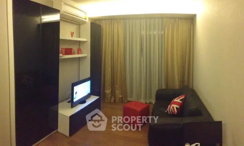 Cozy living room with modern decor and stylish furniture, featuring a sleek black sofa and entertainment unit.
