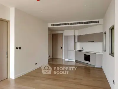Modern open-plan kitchen with sleek cabinetry and hardwood floors in a spacious apartment.