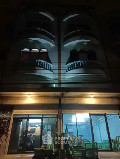 Charming multi-story building with unique architectural balconies and illuminated entrance, perfect for urban living.