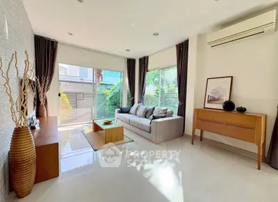 Modern living room with large windows, stylish furniture, and natural light.