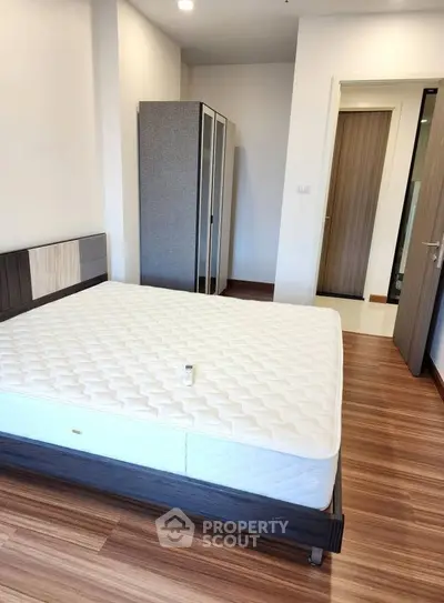 Spacious bedroom with modern wooden flooring and a comfortable bed, perfect for relaxation.