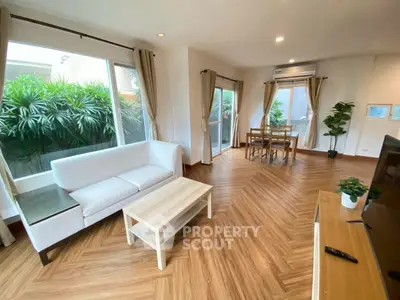 Spacious living room with modern decor and large windows overlooking greenery.