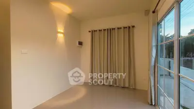 Spacious room with large windows and elegant curtains, perfect for natural light.