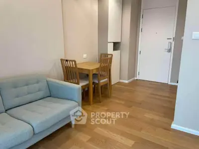 Modern apartment interior with cozy living area and dining space, featuring wooden flooring and neutral tones.