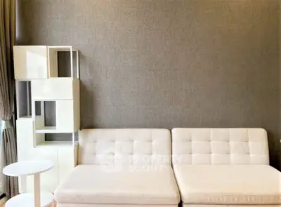 Modern living room with stylish white sofa and unique shelving unit against textured wall.