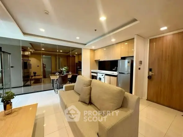 Modern open-plan living room with kitchen, featuring sleek appliances and elegant decor.