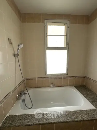Spacious bathroom with elegant bathtub and tiled walls, perfect for relaxation.