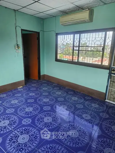 Spacious room with vibrant blue patterned tiles and large window offering natural light.