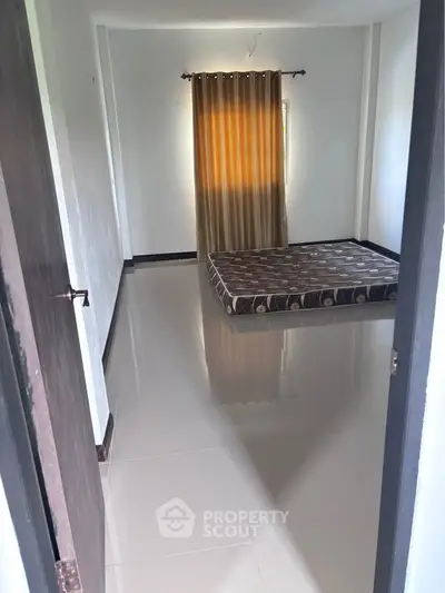 Spacious bedroom with large window and simple decor, perfect for customization.