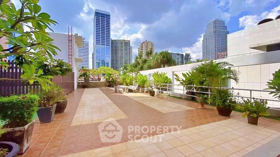 Spacious rooftop terrace with city skyline views and lush greenery.
