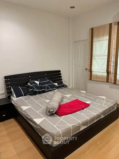 Spacious bedroom with modern decor and natural light, featuring a stylish bed and wooden flooring.