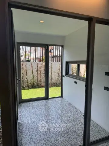 Modern room with large windows and garden view, featuring sleek tile flooring and ample natural light.