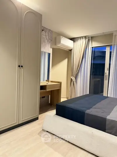 Modern bedroom with sleek design, featuring a large wardrobe, stylish bed, and natural light from a window.