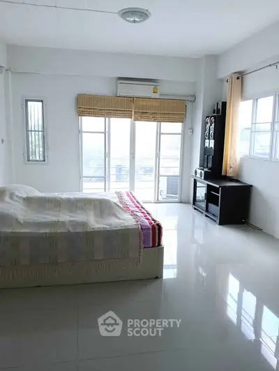 Bright and spacious bedroom with large windows and modern furnishings.