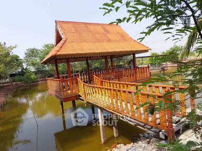 Charming wooden pavilion over tranquil pond with lush greenery, perfect for serene outdoor living.