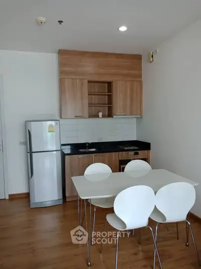 Modern kitchen with wooden cabinets, sleek appliances, and dining area in a stylish apartment.