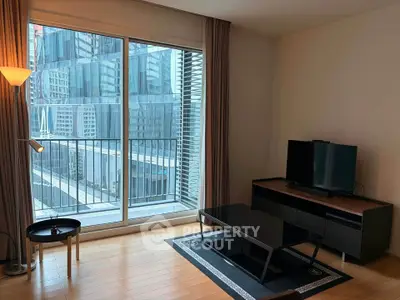 Modern living room with large window and city view, featuring sleek furniture and wooden flooring.
