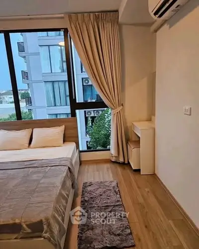 Modern bedroom with large window and wooden flooring in a high-rise apartment.