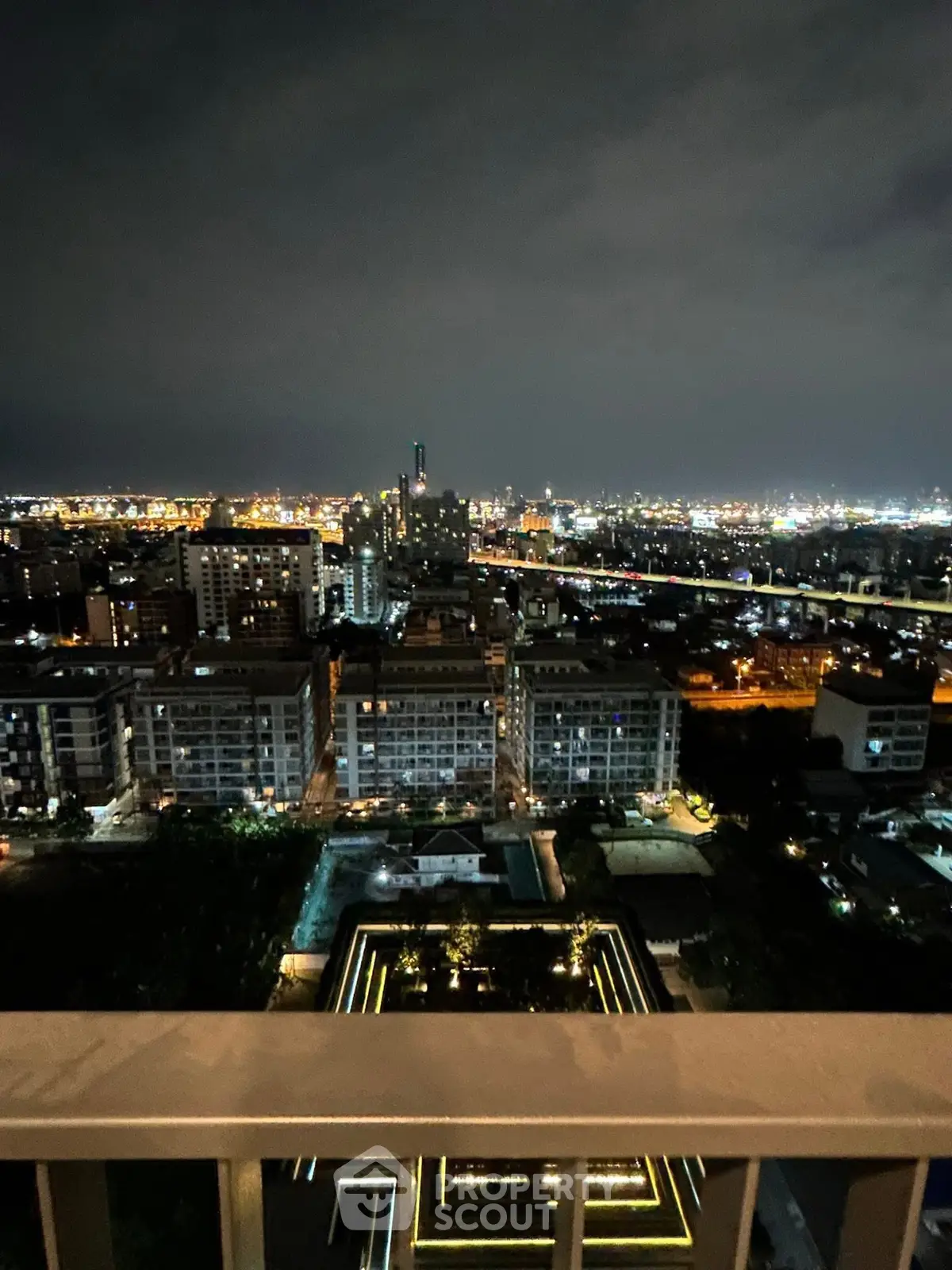 Stunning cityscape night view from a high-rise balcony showcasing urban lights and skyline.