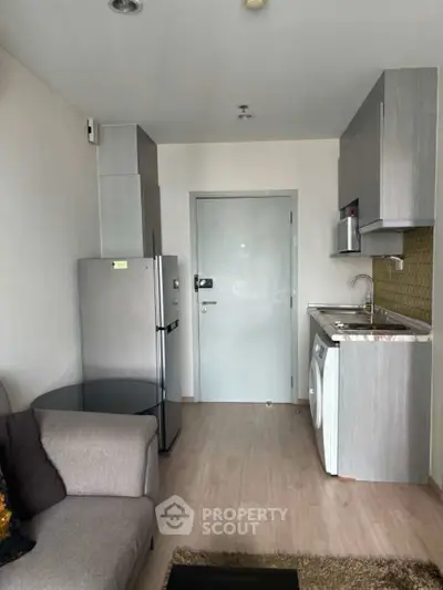 Compact modern apartment with kitchen and living area featuring fridge and washing machine.