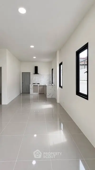 Spacious modern kitchen with sleek tile flooring and ample natural light.