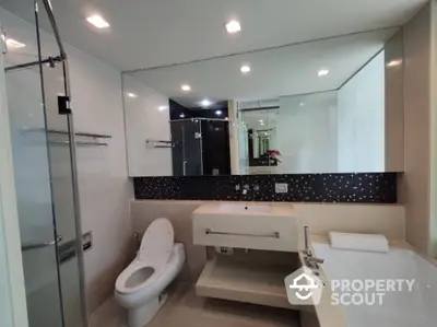 Sleek modern bathroom with wall-mounted fixtures, large mirror, and glass shower enclosure, showcasing a clean and minimalist design.