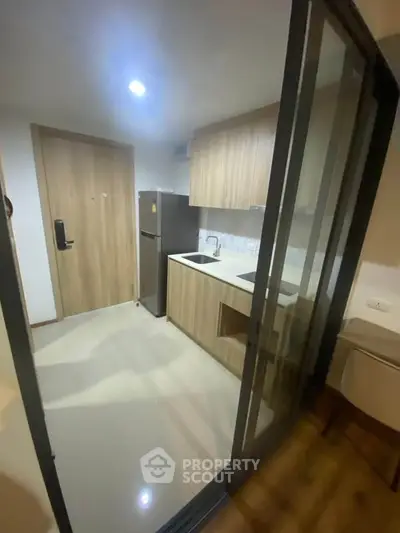 Modern compact kitchen with sleek cabinetry and stainless steel fridge