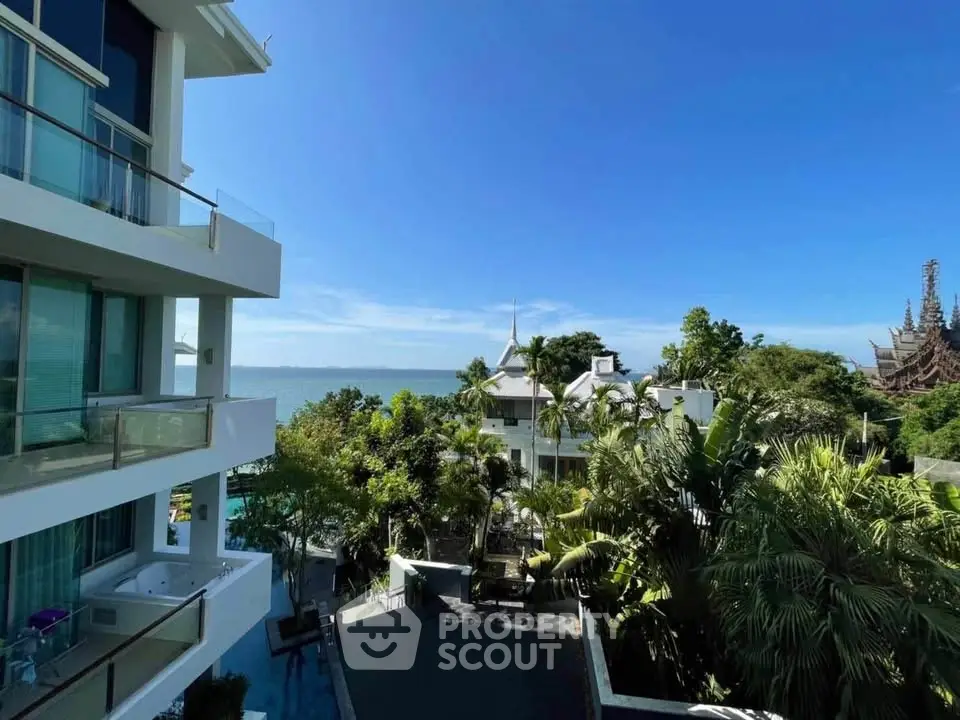 Stunning ocean view from modern apartment balcony with lush greenery and architectural beauty.