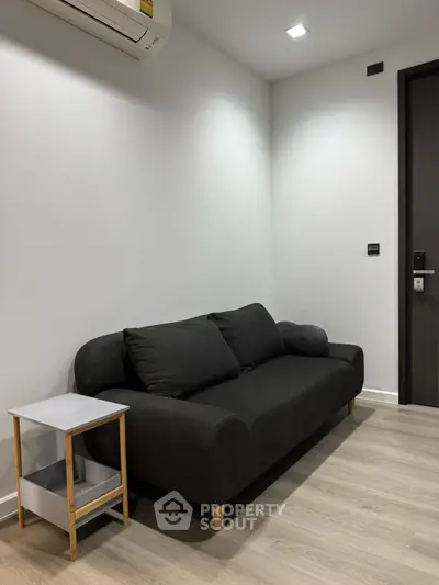 Modern minimalist living room with sleek black sofa and side table, perfect for urban living.