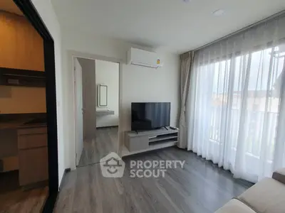 Modern living room with sleek flooring, large window, and wall-mounted TV in a stylish apartment.