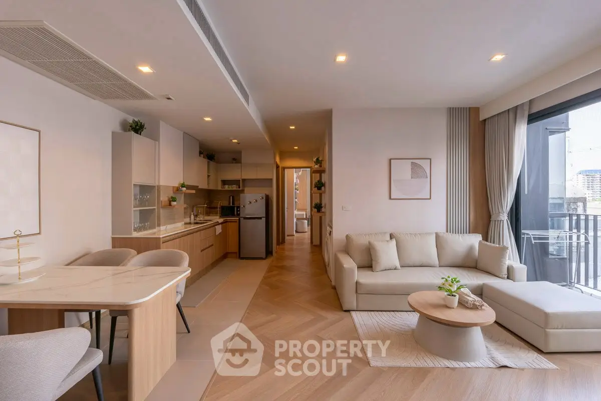 Modern open-plan living room and kitchen with elegant decor and balcony view.