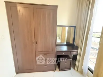 Elegant bedroom with wooden wardrobe and dressing table near balcony