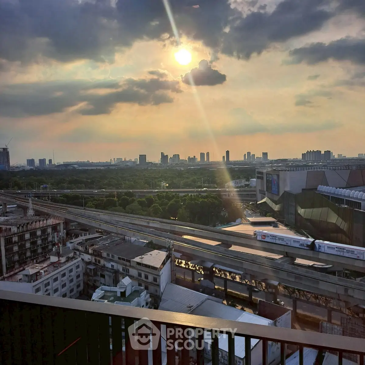 Stunning cityscape view from a high-rise balcony at sunset, showcasing urban skyline and transit lines.