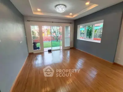 Spacious living room with wooden flooring and garden view through large windows.