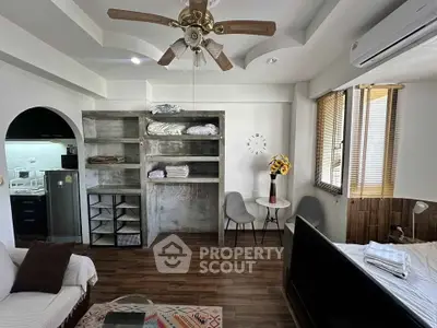 Charming studio apartment with modern decor, featuring a cozy living area, stylish ceiling fan, and compact kitchen.