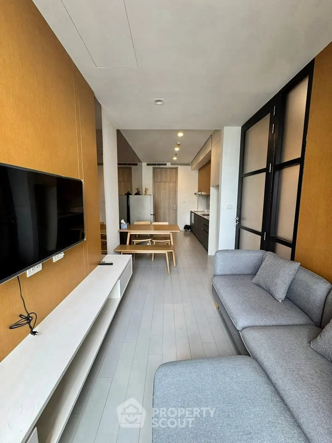 Modern living room with sleek furniture and open kitchen layout in a stylish apartment.
