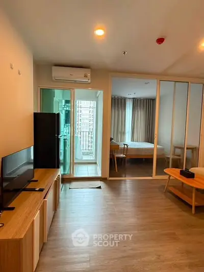 Modern apartment interior with open living room and bedroom, featuring wooden flooring and sleek furniture.