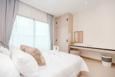 Elegant bedroom with plush bedding and natural light, featuring a stylish wardrobe and vanity area.
