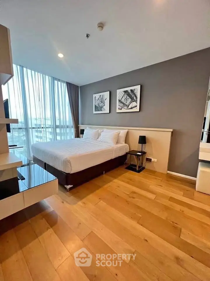 Modern bedroom with wooden flooring and large windows in a stylish apartment.
