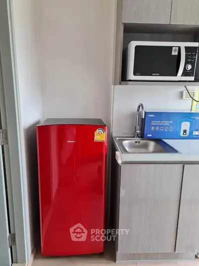 Modern kitchen with red fridge and microwave in compact layout