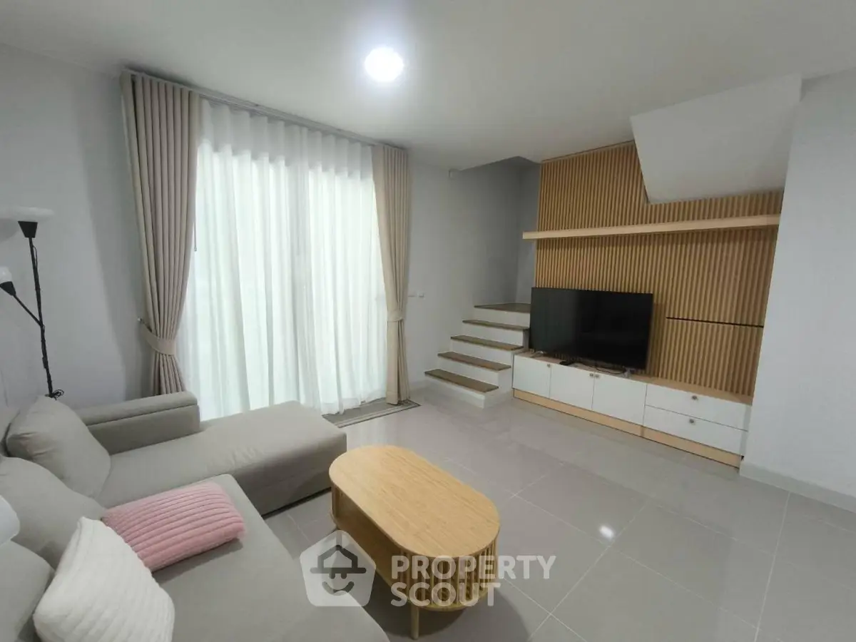 Modern living room with sleek design, featuring a cozy sofa, stylish TV unit, and large window for natural light.