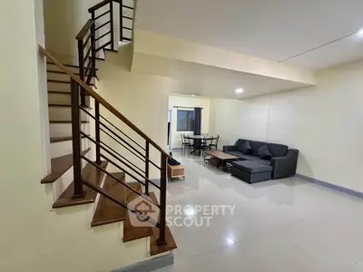 Spacious living room with modern staircase and cozy seating area in open layout.