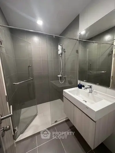 Modern bathroom with glass shower enclosure and sleek vanity in contemporary apartment.
